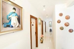 a hallway with a painting of a man holding apron at Hotel O Vince Villa in Bukit Mertajam