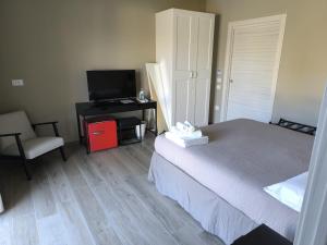 a bedroom with a bed and a television and a chair at Archè Agriturismo in Gioia del Colle