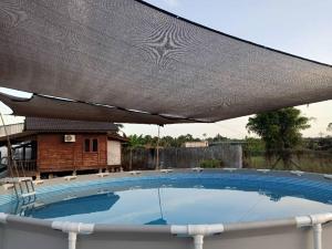 a large swimming pool with an umbrella over it at Hotel O Sri Ayu Inn in Kampung Gurun