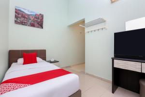 a bedroom with a bed and a flat screen tv at Hotel O Come Inn Premium in Kuala Terengganu