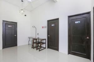 three doors in a room with a table in the middle at Hotel O Come Inn Premium in Kuala Terengganu