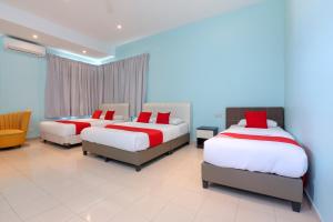 a bedroom with three beds and a couch at Hotel O Come Inn Premium in Kuala Terengganu