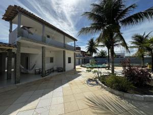ein Haus mit einer Palme und einer Terrasse in der Unterkunft Chalé Casa da Barra in Barra de São Miguel