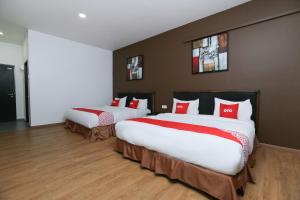 two beds in a hotel room with red pillows at OYO 89915 East Mount Hotel in Kukup