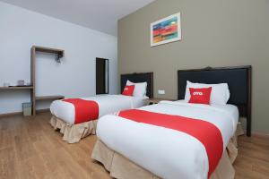 two beds in a room with red and white at OYO 89915 East Mount Hotel in Kukup