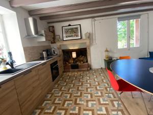 a kitchen with a table and a fireplace at La Petite Grande Maison près de Chauvigny in Fleix +21 photos