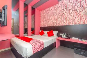 a pink bedroom with a bed with red pillows at Hotel O Rooms Boutique Hotel in Johor Bahru