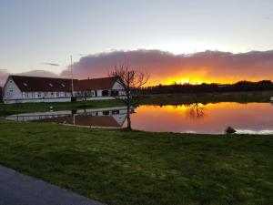 a building next to a lake with the sunset in the background at Fishermans House Apartment 2 in Hirtshals
