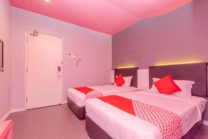 a bedroom with two beds with red pillows at Hotel O Rooms Boutique Hotel in Johor Bahru