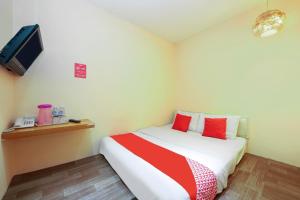 a bedroom with a bed with red pillows and a tv at OYO 479 The Green Hotel in Ampang