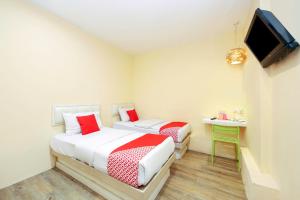 two beds in a small room with a tv at OYO 479 The Green Hotel in Ampang