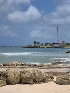 a beach with rocks and the ocean with a sail boat at Uthelina in Saint Peter