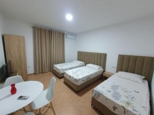a room with two beds and a table and chairs at Residenca Juli in Vlorë