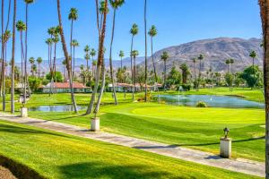 a golf course with palm trees and a pond at Rancho Las Palmas Golf Escape in Rancho Mirage
