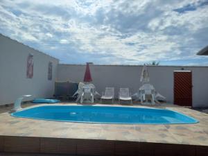 a swimming pool with chairs and a table and a umbrella at Casa na praia in Caraguatatuba +8 photos