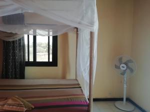 a bedroom with a bed with a fan and a window at Maison Manour chambre 'soft breeze' in Mbour +4 photos