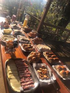 einen langen Tisch mit verschiedenen Arten von Gebäck in der Unterkunft recanto mineiro in São Lourenço + 16 Fotos