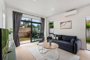 un soggiorno con un divano blu e un tavolo di Sunny Seaside Retreat - Papamoa Beach a Papamoa