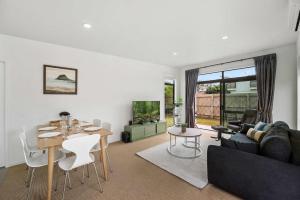 un soggiorno con un tavolo e un divano di Sunny Seaside Retreat - Papamoa Beach a Papamoa