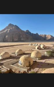 a group of domes in a desert with a mountain at Sun rise wadi rum camp in Wadi Rum