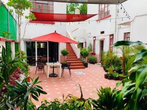 eine Terrasse mit einem Tisch und einem roten Sonnenschirm in der Unterkunft Casa Luna in Mexiko-Stadt