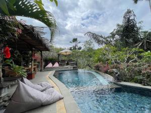 a swimming pool in a garden with a resort at The Asri Villas in Jembrana