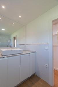 a white bathroom with a sink and a mirror at Finca Tolombreo Casa Chuchi in Cudillero
