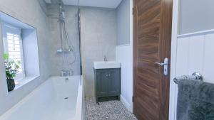 a bathroom with a shower and a tub and a sink at Beau Townhouse in Beaumaris