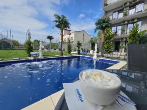 a cup of coffee sitting on a table next to a swimming pool at Grand Bahia Relaxury in Costinesti
