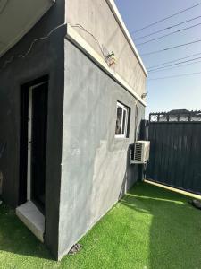 莱基Private Fully Serviced Studio Apartment At Ilasan lekki ikate, AC, Toilet is Shared, Netflix,WiFi,prime,private kitchen的黑灰色的房子,有窗户和绿色的草