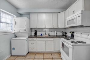 a kitchen with white appliances and white cabinets at Beachside Cottage Home - Short Walk to the Beach in Jacksonville Beach