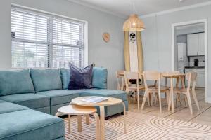 a living room with a blue couch and a table at Beachside Cottage Home - Short Walk to the Beach in Jacksonville Beach