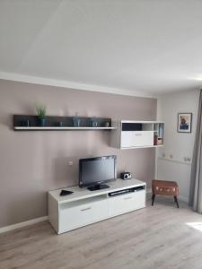 a living room with a tv on a white cabinet at Steiner Strandappartements Appartement 207 Süd- Landseite in Stein +6 photos