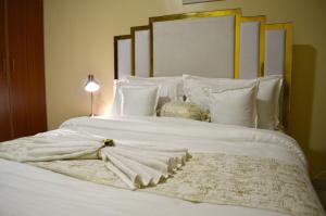 - un lit avec des draps et des oreillers blancs dans l'établissement Modern & Serene 1 BR Getaway, à Eldoret