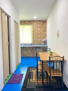 a table and chairs in a kitchen with blue floors at Villa Hajah Rugayah Bakri MUAR in Muar