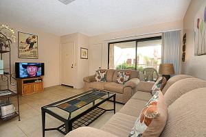 a living room with a couch and a tv at Biarritz Mirage - 1BR Downtown Condo in Palm Springs