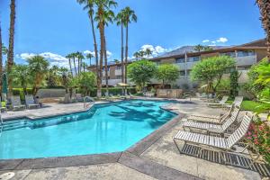 a resort pool with lounge chairs and palm trees at Biarritz Mirage - 1BR Downtown Condo in Palm Springs
