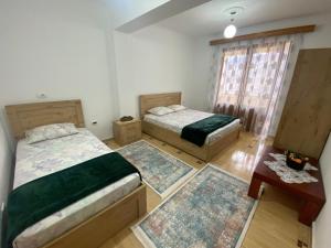 a bedroom with two beds and a table and a window at Vila Përmbi Tepelenë in Tepelenë +27 photos