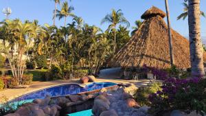 a resort with a swimming pool and a thatch roof at Exclusive Glamping Resort Puerto Vallarta in Puerto Vallarta