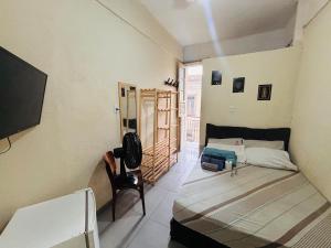 een kleine kamer met een bed en een stoel. bij Pequena Suíte Individual 304 in Rio de Janeiro