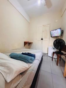 een kamer met twee bedden en een televisie en een tafel bij Pequena Suíte Individual 304 in Rio de Janeiro