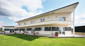 a large white building with a green lawn at Hotel Résidence La Gioia in Sausheim