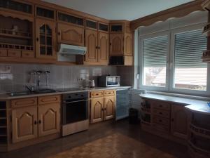 a kitchen with wooden cabinets and a sink and a microwave at VILA RUŽA - Grand apartman 2 in Soko Banja