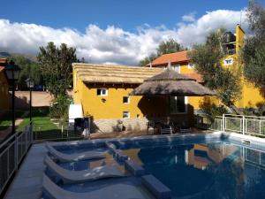 a pool with chairs and an umbrella next to a building at Cabañas Pio Pio in Merlo