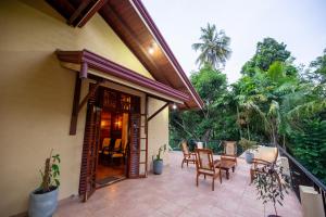 a patio with chairs and a table on a balcony at Petit Paradis Hiriketiya in Hiriketiya