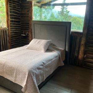 a bedroom with a bed and a large window at Cabañas Campestres Monte Verde in Sutatausa