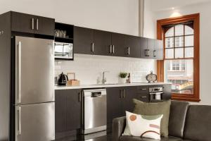 a kitchen with a stainless steel refrigerator and a couch at NEW - 2BRD CBD Apartment in Gisborne