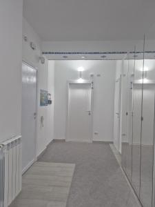 un corridoio vuoto con pareti bianche e porte in vetro di Beach Rooms 2 Self Check-in ad Alghero