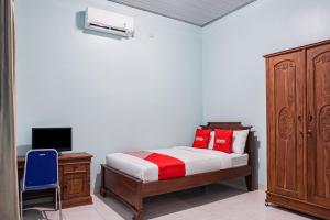班达楠榜OYO 93695 Guest House Riharti Syariah的一间卧室配有一张带红色枕头的床和一张书桌