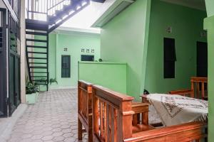 班达楠榜OYO 93695 Guest House Riharti Syariah的一间设有木凳和绿色墙壁的客房